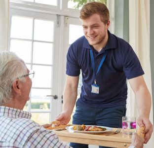 A carer passing a meal to a gentleman