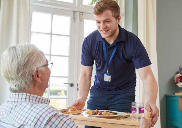 A carer passing a meal to a gentleman