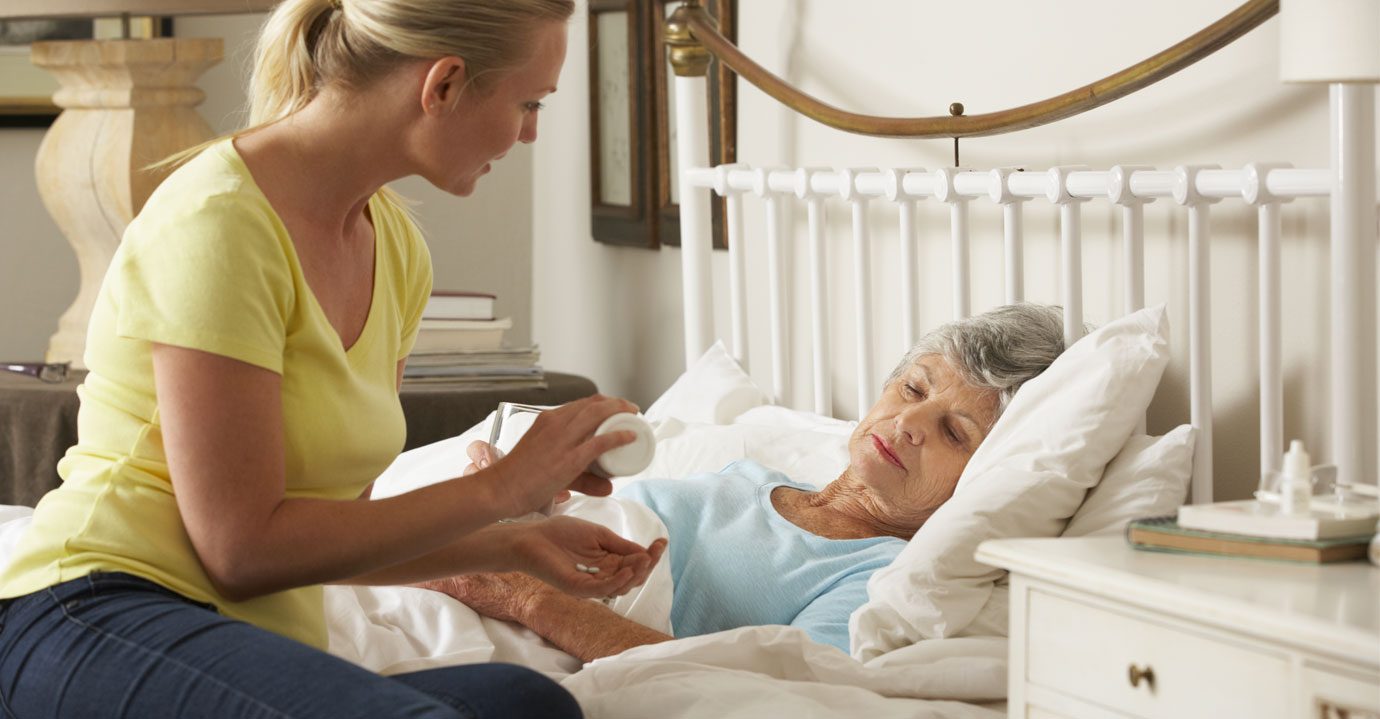 A carer comforting a lady in bed