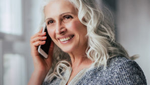 Lady smiling on the phone whilst drinking a coffee