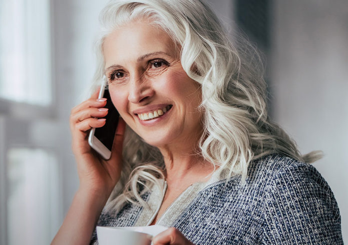 Lady smiling on the phone whilst drinking a coffee