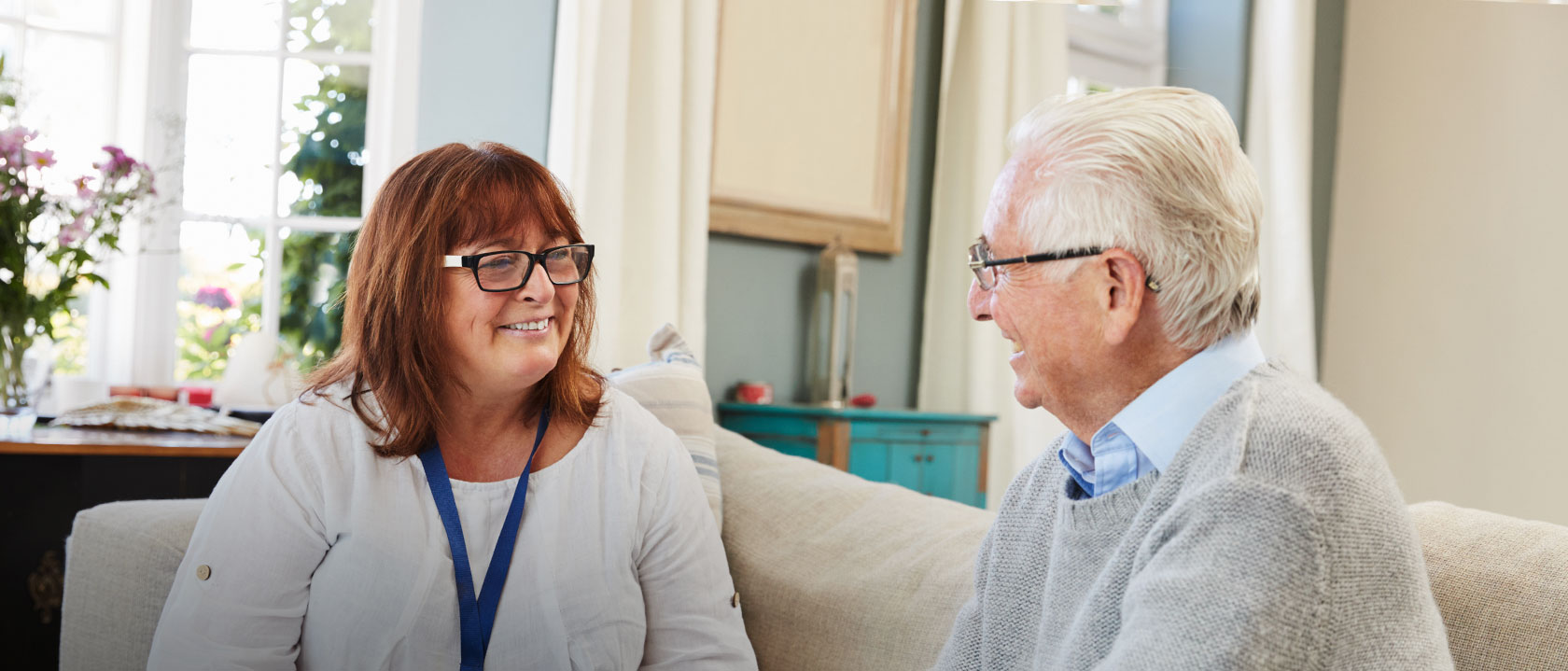 Care worker chatting to a man on the sofa