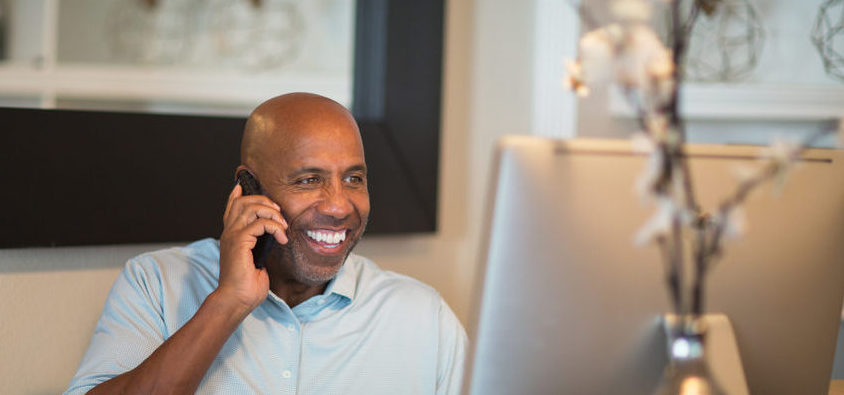 A man using a computer whilst on the phone