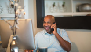 A man using a computer whilst on the phone