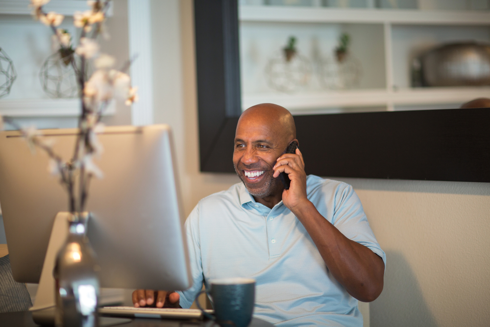 A man using a computer whilst on the phone